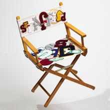 Load image into Gallery viewer, A wooden folding chair with a vintage chenille patch on the backrest, featuring abstract and colorful designs.

